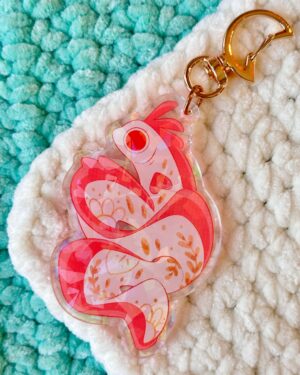 Translucent pink butterfly-shaped keychain with a gold ring on a white and teal fluffy rug backdrop.