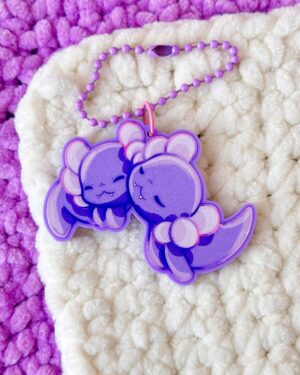 Close-up of a lavender bead bracelet with a purple flower-shaped charm on a cream-and-purple plush rug.