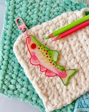 Close-up of a teal and white fluffy rug with a pink zipper pull and two colored pencils (green and pink).