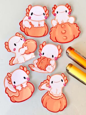 Colorful cartoon crabs stickers with orange bodies, red outlines, and pink cheeks scattered on a light surface near markers
