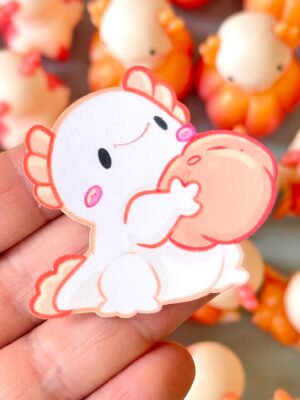 Close-up of a cute white cartoon chick sticker with pink outlines being held between fingers